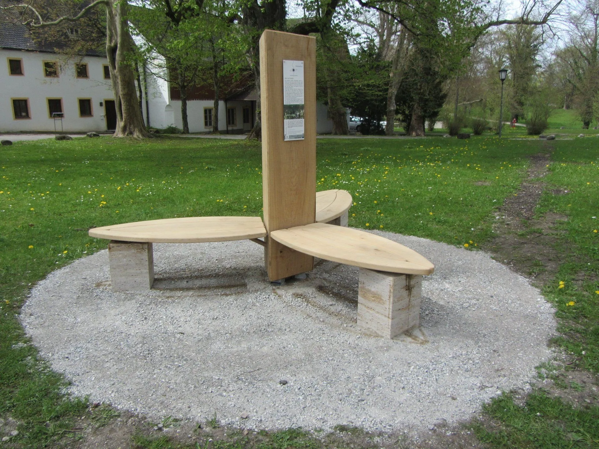 Rundbank aus massivem Holz auf einem Kiesplatz im Freien