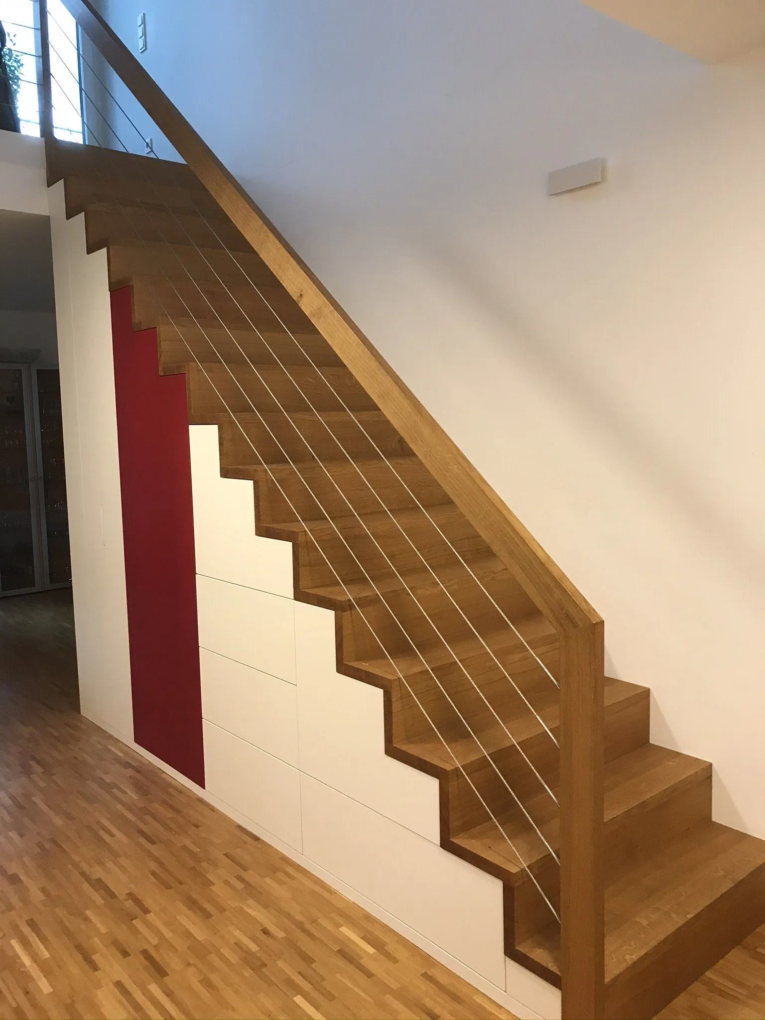 Treppe mit weißem Einbauschrank vor roter Wand