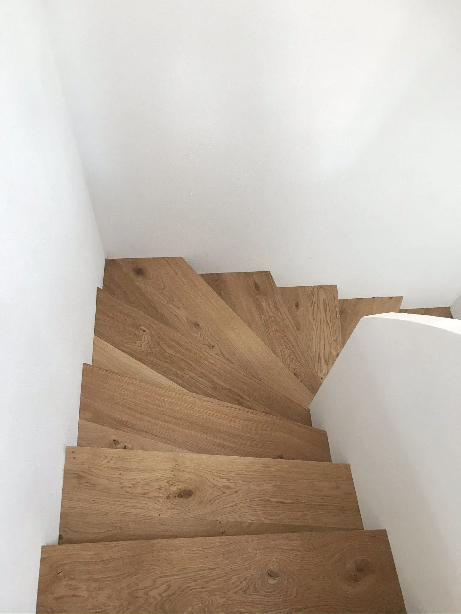 Blick von oben auf einen gewendelten Treppenlauf aus Eiche