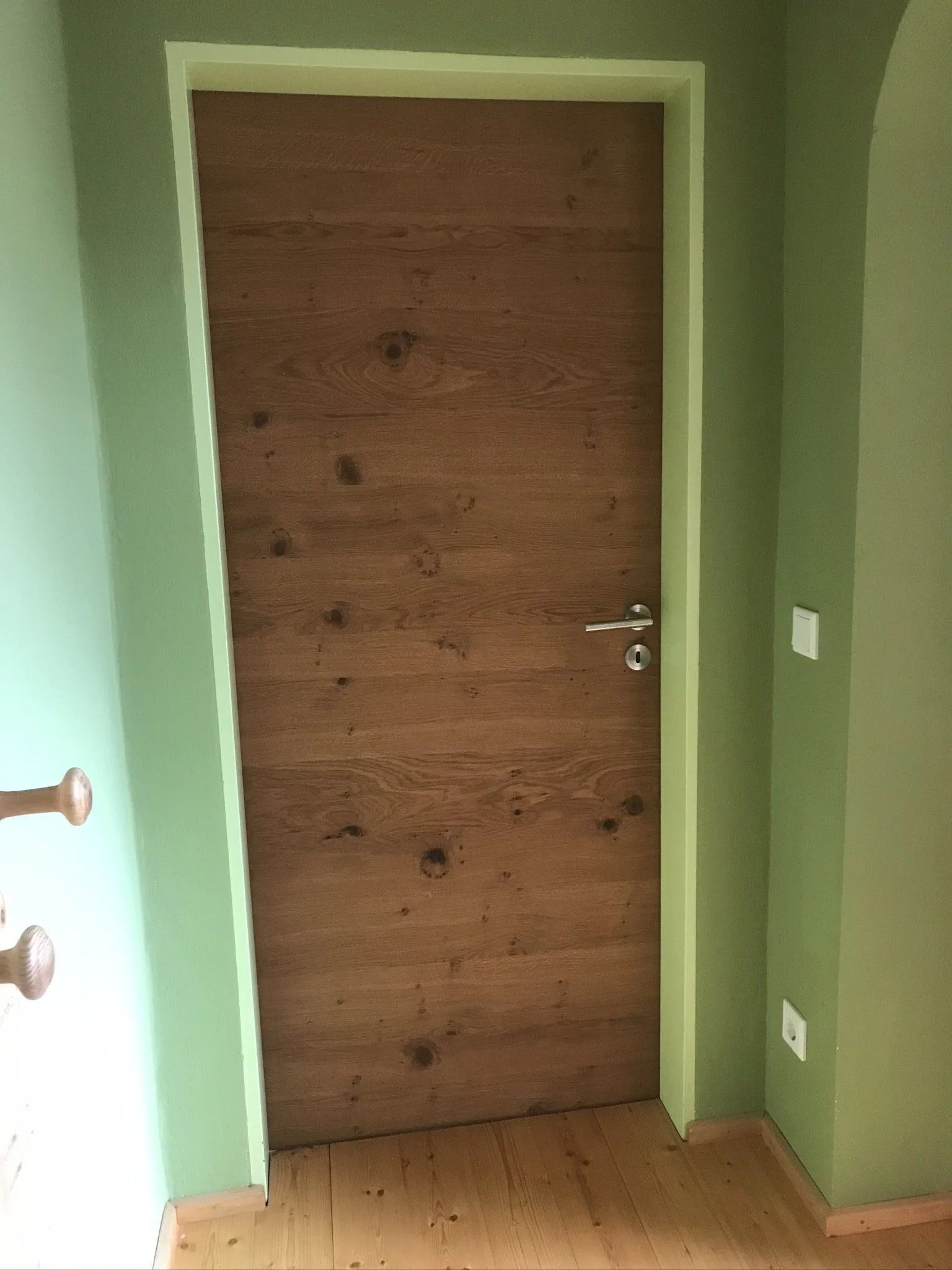 Zimmertür aus Fichte-Altholz vor grün gestrichener Wand
